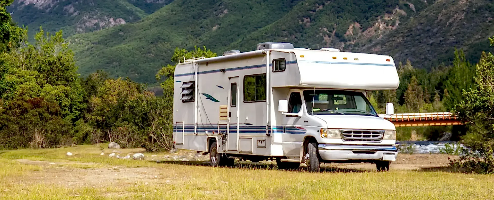 White camper parked in grassy mountain clearing